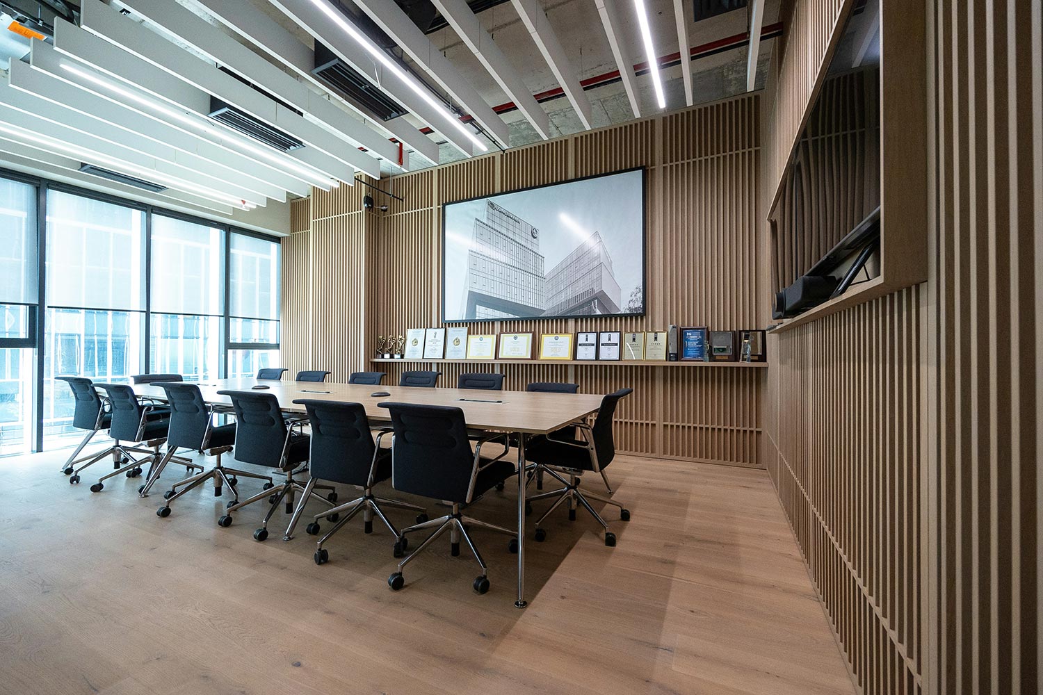 Modern boardroom with a large wooden table, office chairs, and vertical slat walls