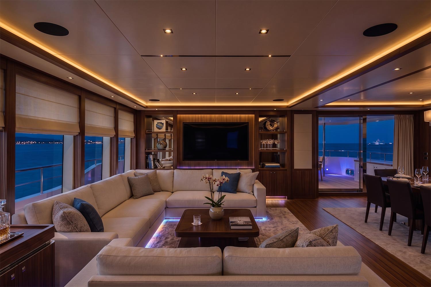 Warmly lit living room featuring a white sectional sofa, floor lamps, and a welcoming ambiance for social gatherings.